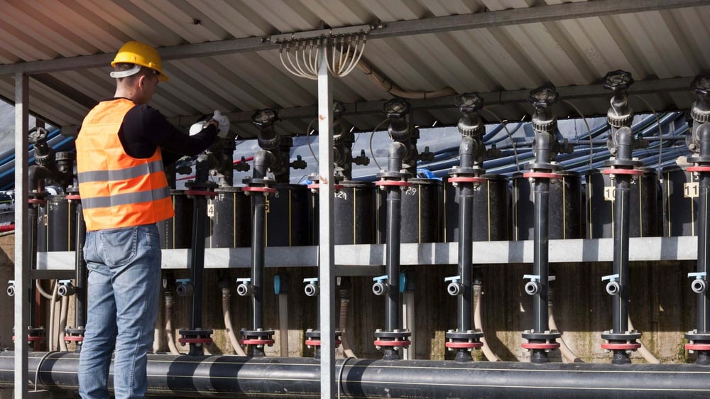 Working in hi-vis jacket and hard-hat working on pipes (opens in new window)